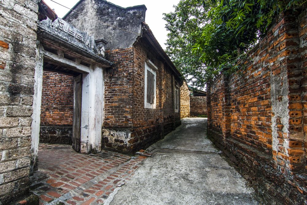 Old brick construction with red tiled roof, wall and gate in the Duong Lam ancient village, Vietnam